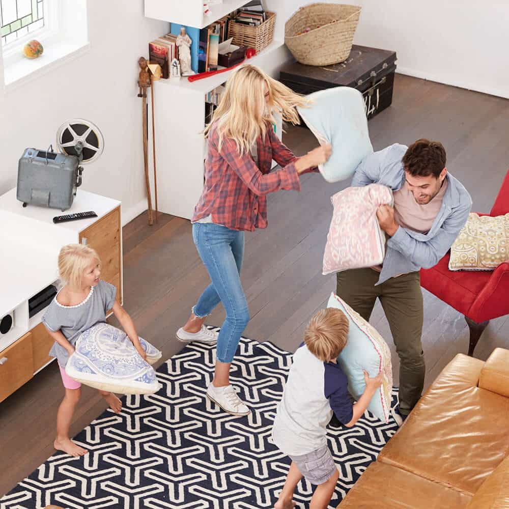 Junge Familie spielt im Wohnzimmer mit Kissen